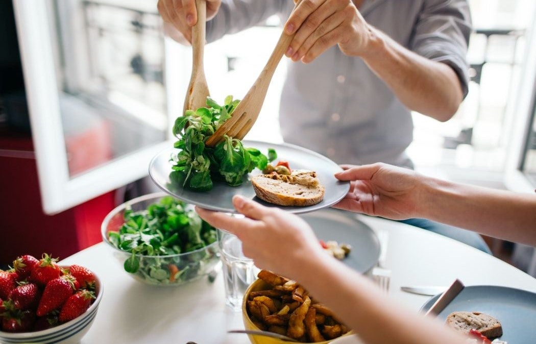 Serving a fresh salad onto a plate in a bright kitchen.