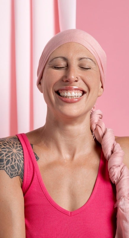 Person wearing a pink headscarf and sleeveless top against a pink background.